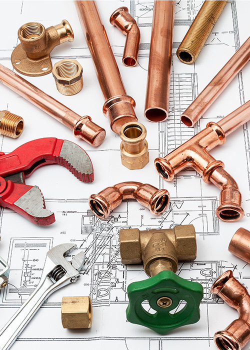 Plumbing tools and copper fittings laid out on construction drawings
